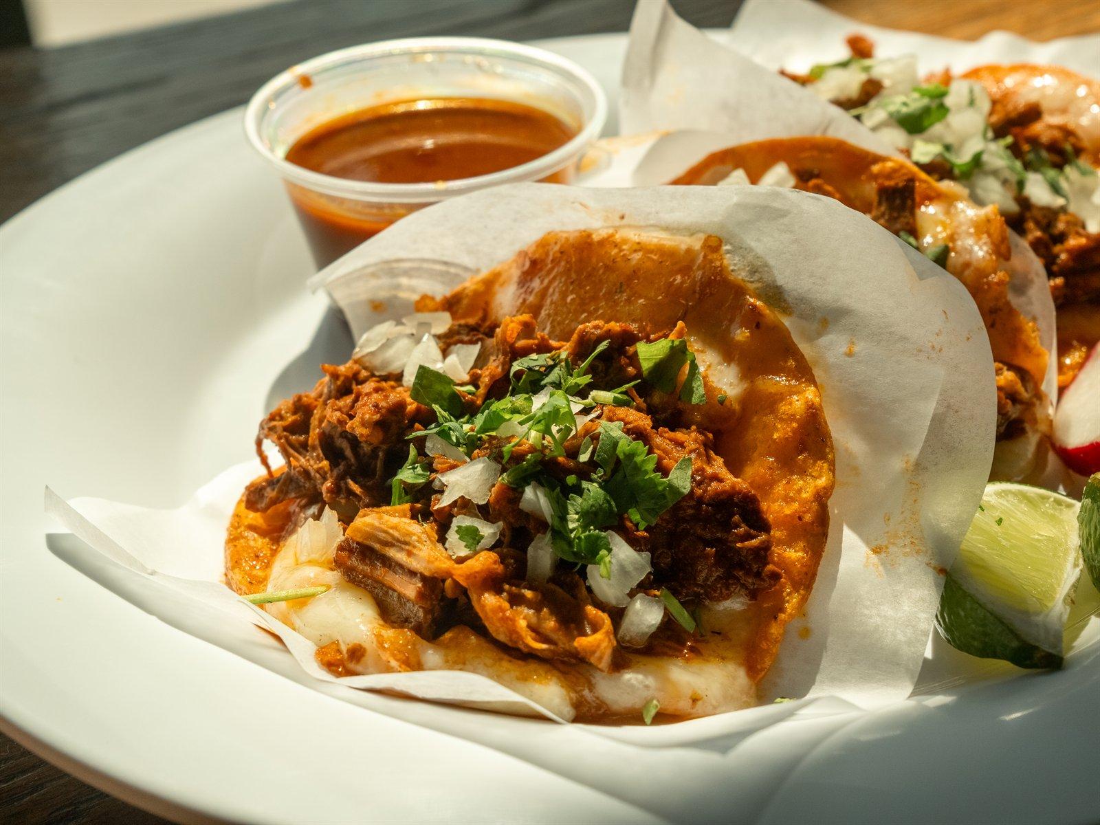 Close-up red queso taco with a cup of consommé