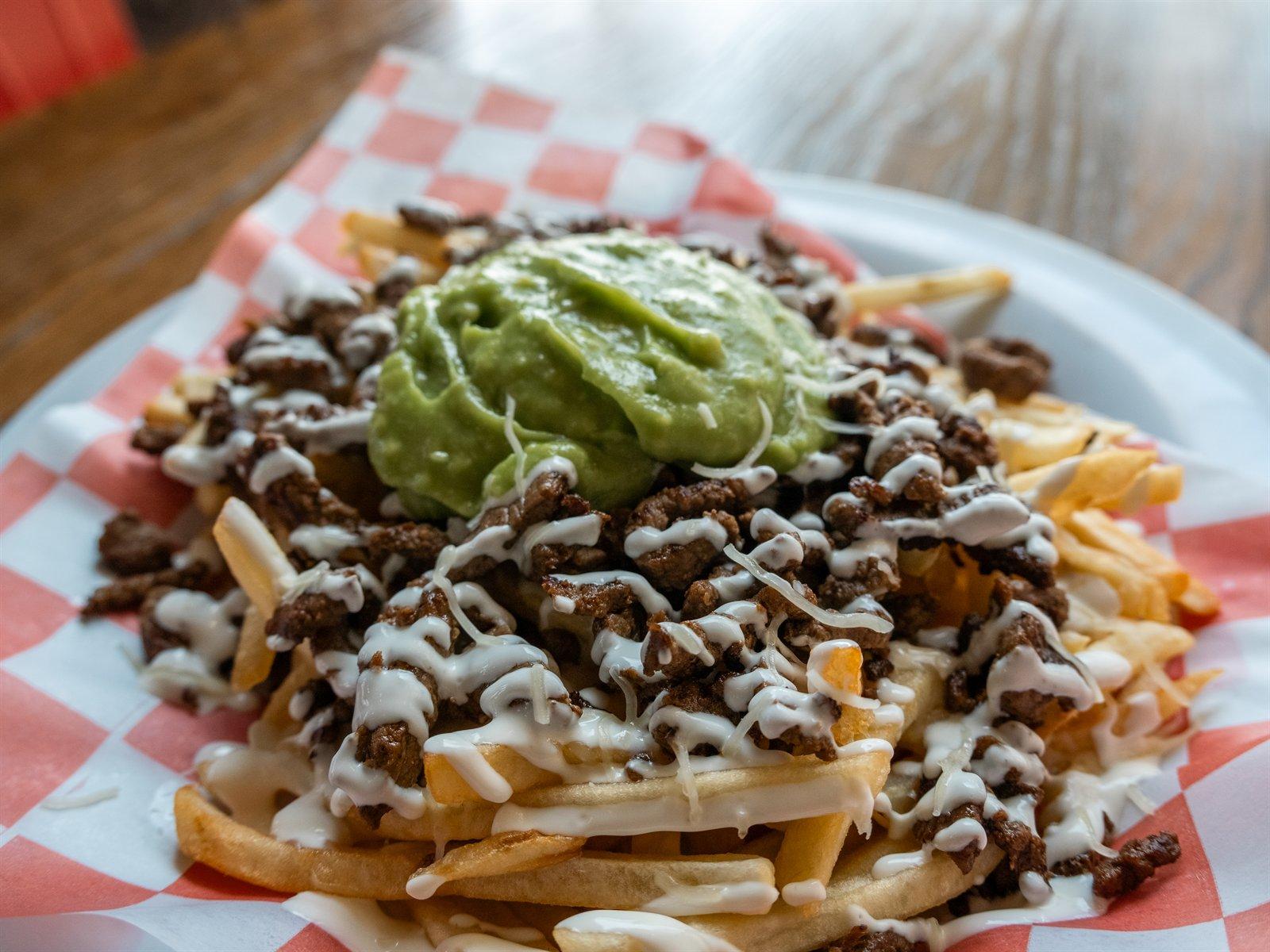Loaded asada fries with guacamole in a basket